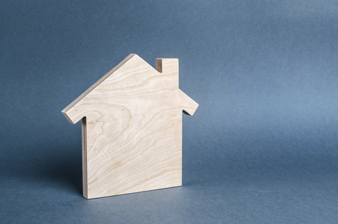 Wooden cutout of a home in front of a gray background